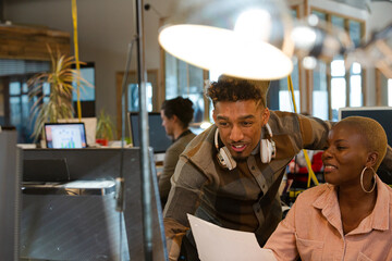 Man and woman discussing paperwork at computer