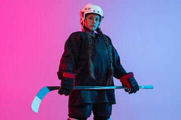 Discipline. Portrait of child girl - professional hockey player isolated over gradient pink purple background.