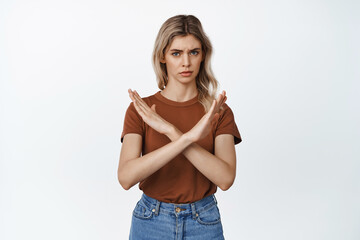 Confident and serious blond girl making hand cross gesture, stop forbid sign, rejecting and saying...
