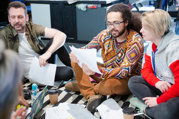 Team sitting on office floor, discussing paperwork