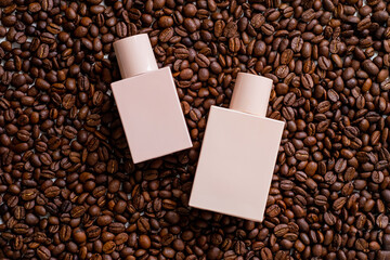 Two begie perfume bottles lies on roasted grains of black coffee beans. Perfume bottle mockup, blank cosmetic bottles template. Package design.