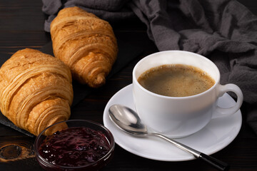 fresh croissants with jam and coffee on dark background. French breakfast