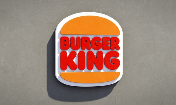 Three-dimensional logo of fast food chain Burger King against neutral wall. Editorial 3D illustration