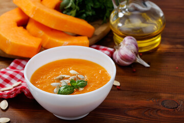 Pumpkin and carrot soup with pumpkin seeds on wooden background