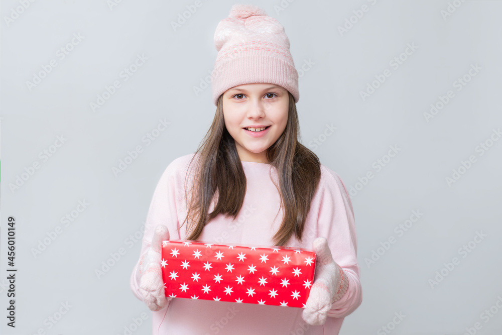 Wall mural Child with a Christmas present. Happy girl with box in sweater and hat