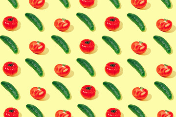 Creative pattern made of fresh raw red tomatos and green cucumbers on yellow background. Healthy food concept.
