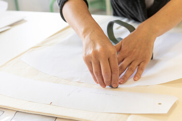 Obraz na płótnie Canvas A woman draws and cuts a clothing pattern