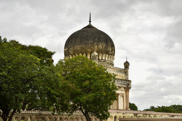 Obraz premium Antique Islamic Architectural Art Pointed Arches Seven Tombs Dome and Blue Sky Green Trees