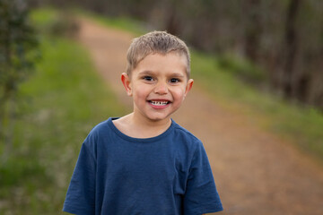 young kid outdoors smiling and looking at camera