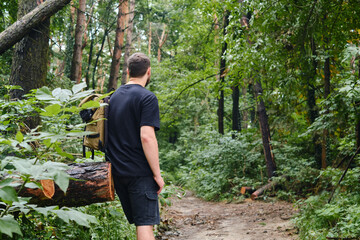A man traveler walks through the woods. Beautiful wild nature landscape in forest. Hiking journey on tourist trail. Outdoor adventure. Travel and exploration. Healthy lifestyle, leisure activities