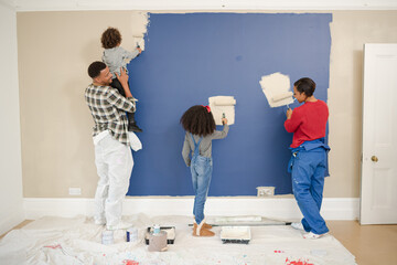 Happy, playful family with paint rollers painting room