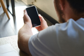 A man is holding a modern smartphone, sending a text message or using an application on his mobile phone. Business concept. Smartphone close-up. Focus on the phone screen