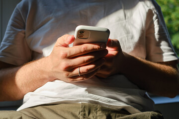 A man is holding a modern smartphone, sending a text message or using an application on his mobile phone. Business concept. Smartphone close-up. Focus on the phone screen