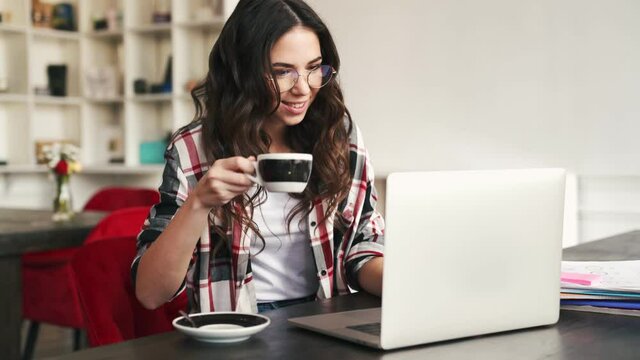 A beautiful woman working with her laptop sitting inside the cafe 