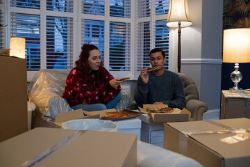 Happy couple taking a break from moving, eating pizza