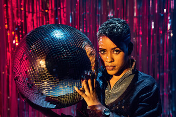 Stylish black model with makeup holding on disco ball