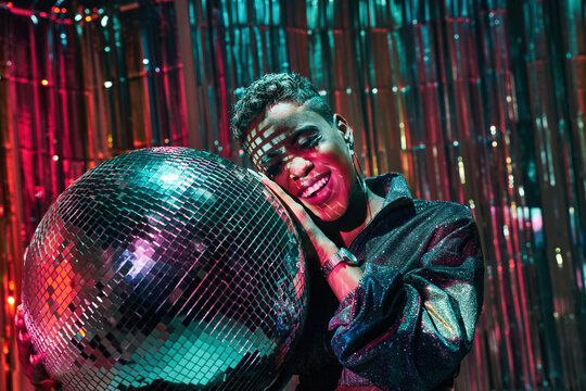 Stylish black model with makeup leaning on disco ball
