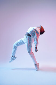 Active black dancer in headset jumping on light background