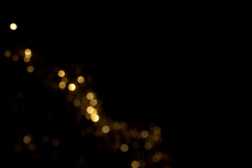 Golden blurred bokeh lights on black background. Glitter sparkle stars for celebrate