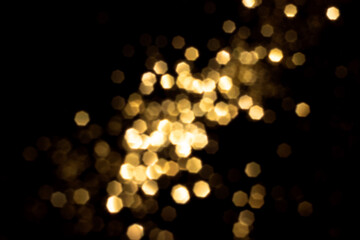 Golden blurred bokeh lights on black background. Glitter sparkle stars for celebrate