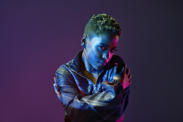 Trendy black model embracing herself in neon light
