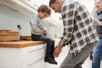 Father putting shoes on son