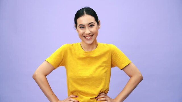A laughing asian woman showing a thumb-up gesture standing isolated over purple background in the studio