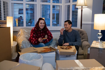 Happy couple taking a break from moving, eating pizza