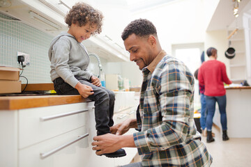 Obraz premium Father putting shoes on son