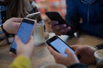 Young adults using smart phones at table