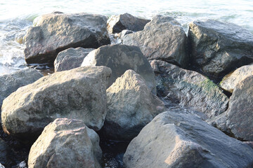 Large stones close-up in sea water in summer on beach against background of sea