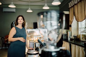 Choosing desserts. Middle age brunette beautiful successful pregnant woman having rest while buying desserts in new bakery.