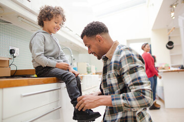 Fototapeta premium Father putting shoes on son