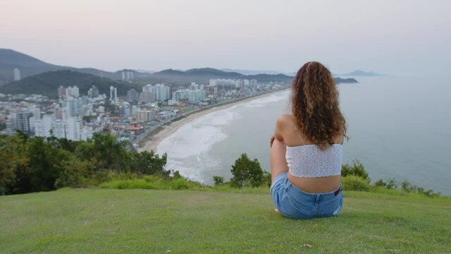 Cute girl admiring the sunset at careca hill, Itajaí, Brazil.