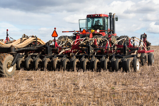 horizontal shot of a tractor plowing soil with cultivator smashing  clods beds on a sunny day