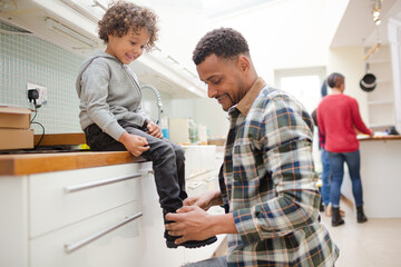 Father putting shoes on son