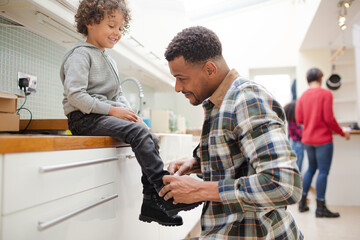 Father putting shoes on son