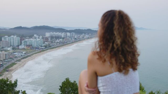 Cute girl admiring the sunset at careca hill, Itajaí, Brazil.