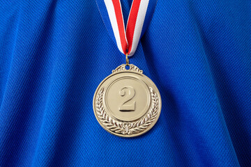 Silver medal. Champion trophy award and ribbon. Prize in sport for winner on blue shirt background