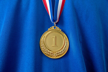Gold medal. Champion trophy award and ribbon. Prize in sport for winner on blue shirt background