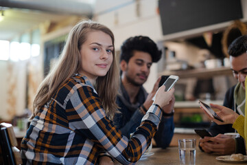 Young adult friends using smart phones at cafe table