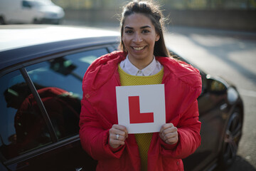 Portrait confident, happy young woman holding learners permit by car