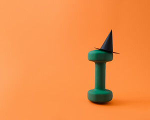 Fitness dumbbell wearing witch hat for funny Halloween health and wellness concept