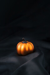 Shiny pumpkin decoration on silky fabric for luxury Halloween concept.