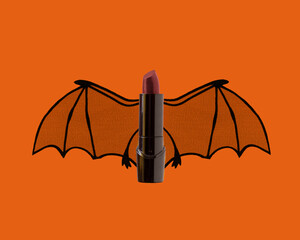 Dark red lipstick with bat wings on orange background for Halloween spooky beauty concept