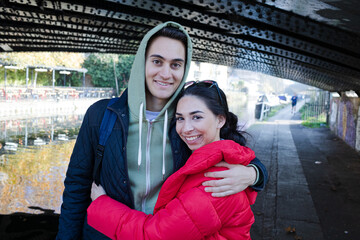 Happy, affectionate young couple hugging under urban bridge