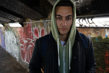 Fototapeta na wymiar Serious young man wearing hoody in urban tunnel