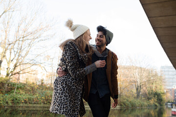 Portrait happy young couple hugging along canal