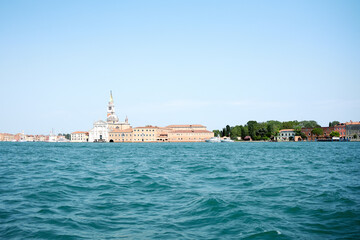 Naklejka premium Venetian gondolier punting gondola through green canal waters of Venice Italy 