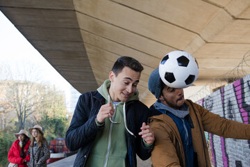 Two young men with soccer ball in urban tunnel